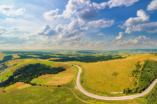 Panoramic aerial view of the countryside, country road, and cultivated and uncultivated fields in the hills