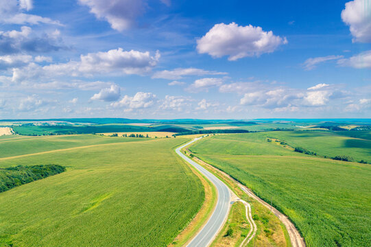 Top view of a highway among cultivated agricultural fields. Rural landscape in summer