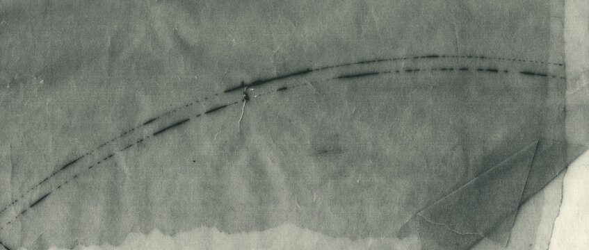 Old translucent tracing paper texture with layered folds, creases, scratches and uneven tonal variations, presented in a panoramic format with a greenish monochrome appearance.
