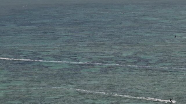 Aerial drone view of kite surfers riding the waves at My Hoa Beach in Vinh Hai, Khanh Hoa, Vietnam, showcasing a spectacular coastal landscape under bright sunlight. 