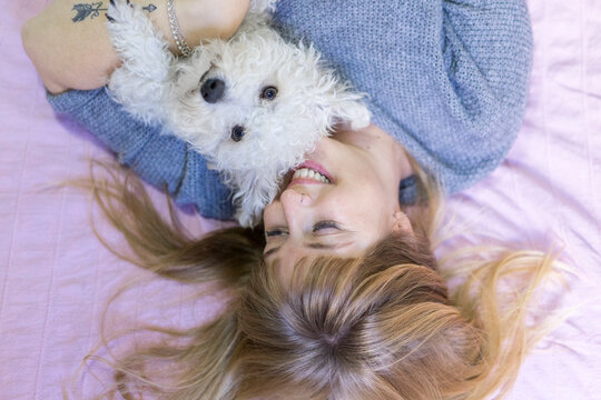 Happy woman lying on bed with her dog