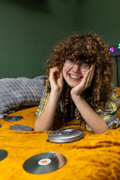 Teenage girl enjoys listening to music on a bed indoors
