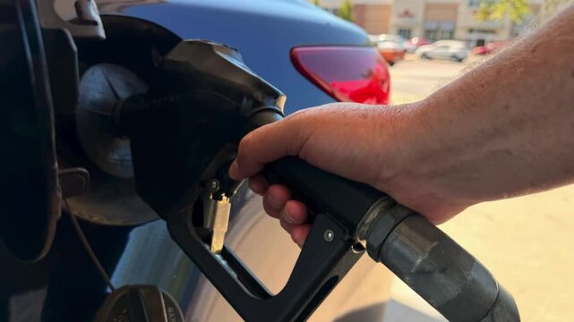 Close-Up of Hand Pumping Gas into Car at Gas Station