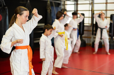 Children athletes starting position and studying and repeating sequence of punches and painful techniques in karate kata technique. Oriental martial arts, training and obtaining black belt. © JackF