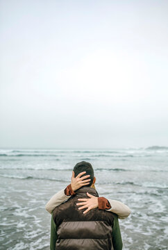Woman embracing man at the seafront in winter