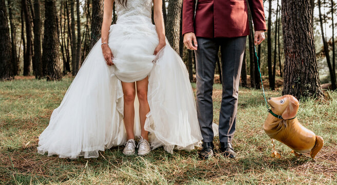 Low section of bride and groom in forest with funny dog-shaped balloon