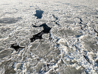 Fototapeta premium Traffic-filled bridge spanning a river filled with drifting ice floes.
