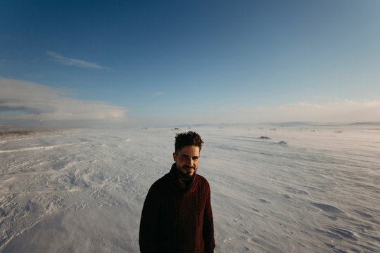 A smiling man stands in a snowy winter landscape in Finland