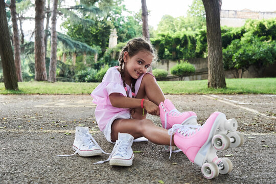 Little girl smiling at camera while putting roller skates on in the park