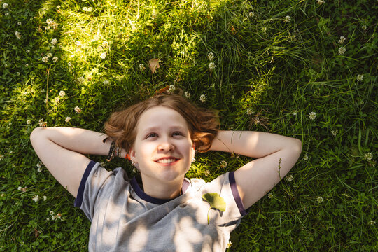 A smiling girl relaxes on green grass during a peaceful summer day