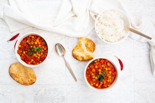 Two bowls feature Indian chana masala with rice and naan bread