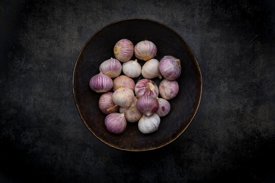 Single clove garlic in a bowl on black concrete