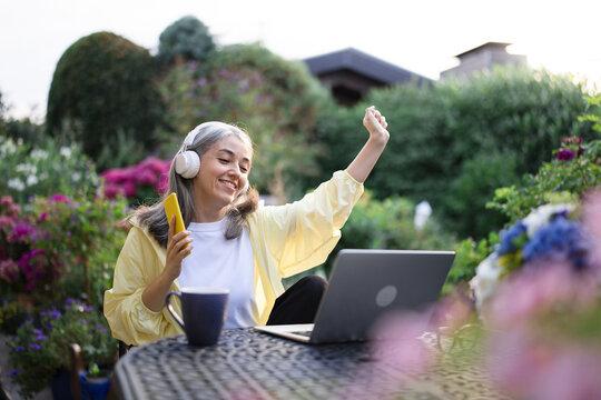 Happy woman listening to music with headphones in home office garden