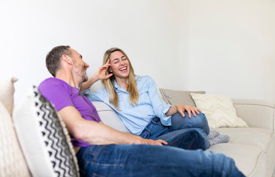 A mature couple shares a funny joke on the sofa at home