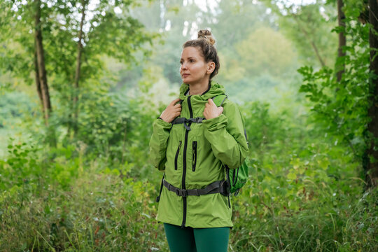 Active woman with backpack hiking in green summer forest