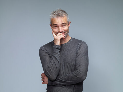 Portrait of smiling mature man with raising eyebrows in front of green background