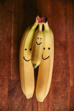 Bunch of two large and one small bananas with smiley faces