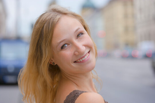 Germany, Bavaria, Munich, Young woman smiling in front of Bavarian State Library at Ludwigstrasse