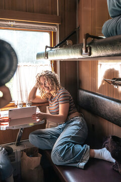 Smiling woman uses a tablet inside a vintage train compartment