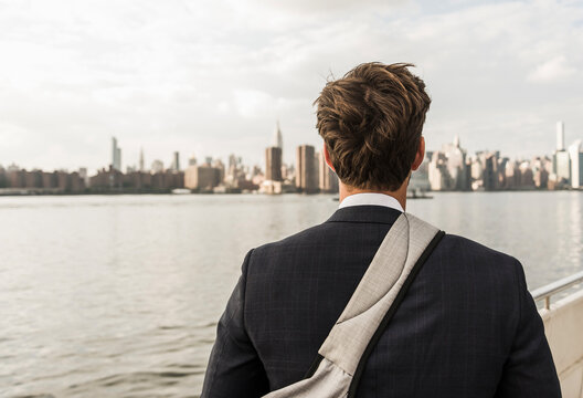 USA, New York City, back view of man at East River looking on Manhattan