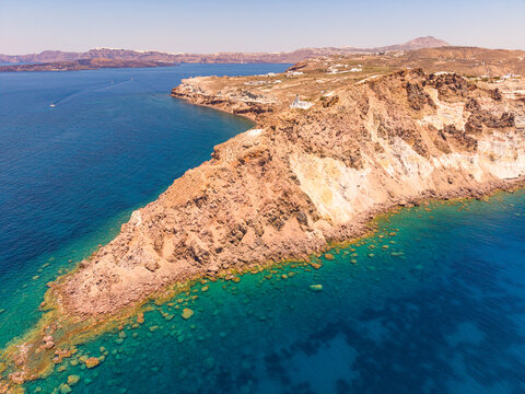 Aerial drone panorama of Cape Akrotiri rocky peninsula and emerald sea in Santorini Greece