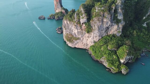 Aerial view of Railay Beach with limestone cliffs rising from the turquoise sea and longtail boats leaving wakes in Ao Nang, Krabi, Thailand.