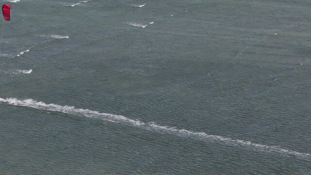 Aerial drone view of kite surfers riding the waves at My Hoa Beach in Vinh Hai, Khanh Hoa, Vietnam, showcasing a spectacular coastal landscape under bright sunlight. 