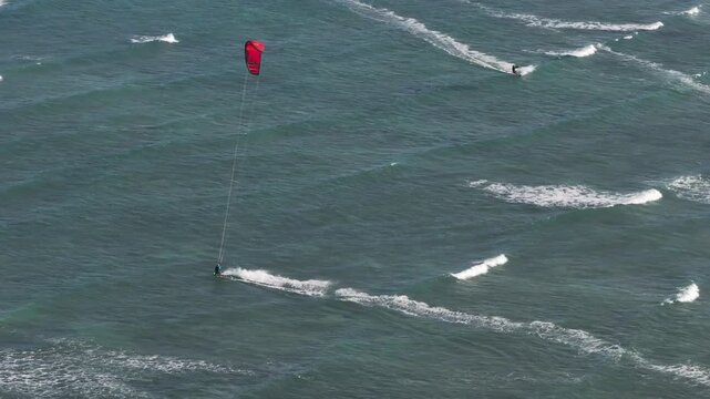Aerial drone view of kite surfers riding the waves at My Hoa Beach in Vinh Hai, Khanh Hoa, Vietnam, showcasing a spectacular coastal landscape under bright sunlight. 