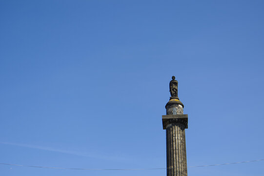 Top of the Melville Monument column with the statue of Henry Dundas against a clear blue sky in St Andrew Square, Edinburgh, Scotland.