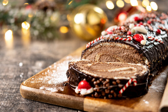 Christmas chocolate yule log cake with festive decorations on wooden table. Copy space