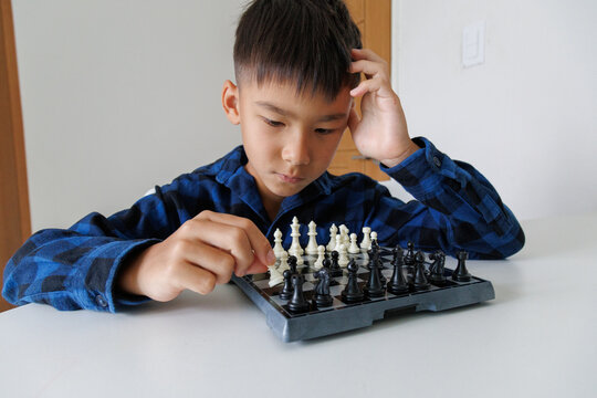 Child thinking about a chess move while playing chess at home, looking at the board and deciding what to do next.