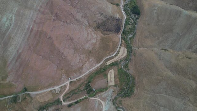 Top-down aerial of eroded Chalus Road hillsides with a pale track crossing dry terraces and a thin green drainage line. Ideal for travel, tourism, and nature stock Iran Alborz mountains.
