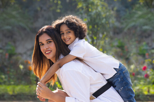 Mother with her son sitting in the park and looking at camera
