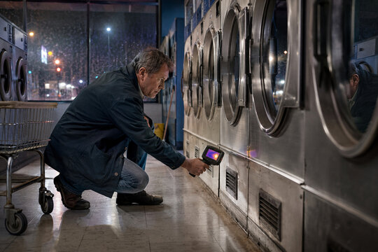 Laundromat owner checking dryers with a thermal camera