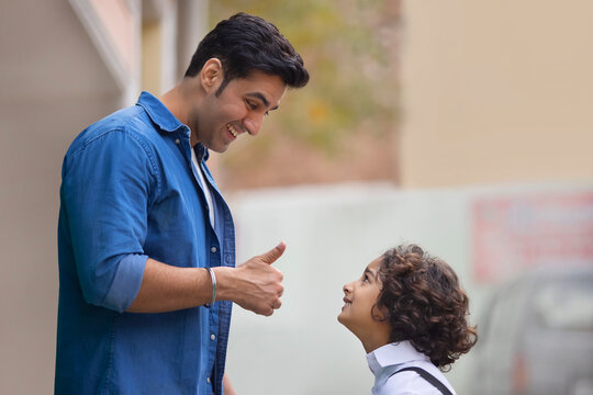 Little school boy getting praise from his father for good work