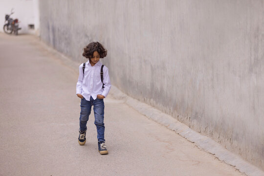 Little boy in school uniform walking down the street to school