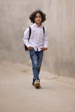 Little boy in school uniform walking down the street to school