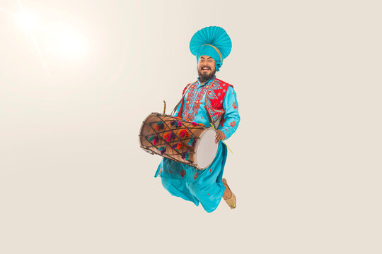 Sikh Man jumping with drum while performing bhangra during Baisakhi Celebration