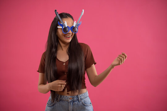 Portrait of a funny young woman wearing guitar shaped eye glasses