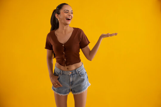 Young woman gesturing while standing against yellow background