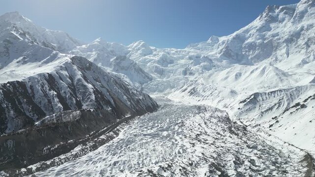 Aerial drone flyover of vast snowfields and towering rocky mountain peaks near Fairy Meadows Base Camp in Hunza Valley, Pakistan. Scenic alpine wilderness