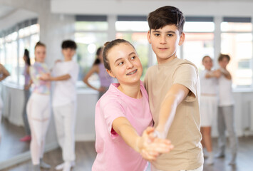 Fototapeta premium Teen girl paired with guy practices movements of waltz dance and trains to perform movements during lesson in choreography studio.