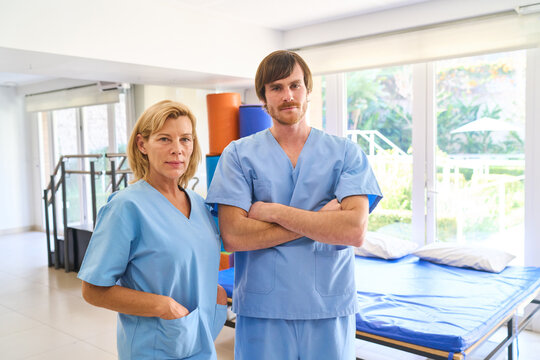 Physiotherapists In Rehab Center Man And Woman Wearing Blue Scrubs Rehabilitation After Injury Indoor Physical Therapy Setting Healthcare