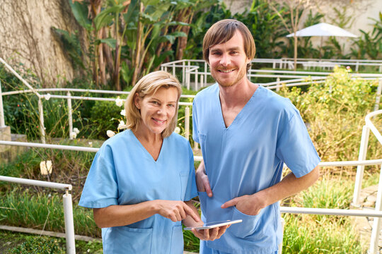 Physiotherapists With Tablet Outdoors In Rehab Center Senior Woman And Man In Blue Scrubs Healthcare Professionals Medical Staff Therapy