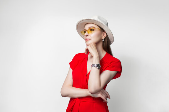 Young girl wearing red dress, white hat and sunglasses isolated on white background.