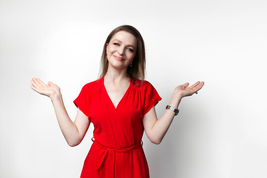 Young girl in red dress raising both hands with open palms on white background.