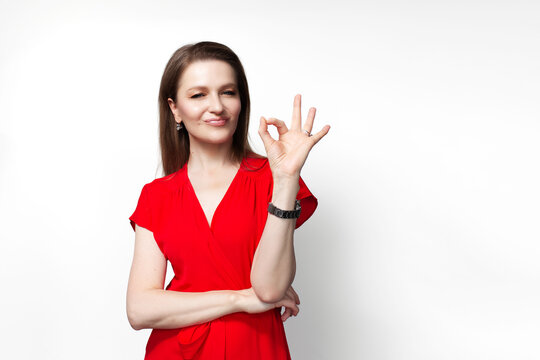 Young girl in red dress showing ok gesture with hand isolated over white background.