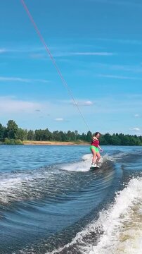 Young woman wakeboarding at high speed, extreme water sports action, adrenaline and athletic performance on the lake