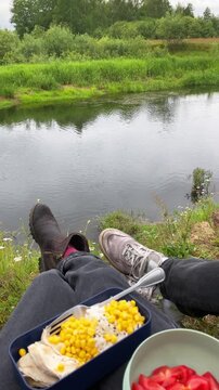 Lunch from a lunchbox outdoors by the river while camping on a trip. Picnic, connection with nature, rest, and relaxation, enjoying the atmosphere of outdoor recreation