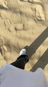 A woman's legs walk along the sandy riverbank. Enjoying the summer atmosphere, and relaxing in nature, hiking